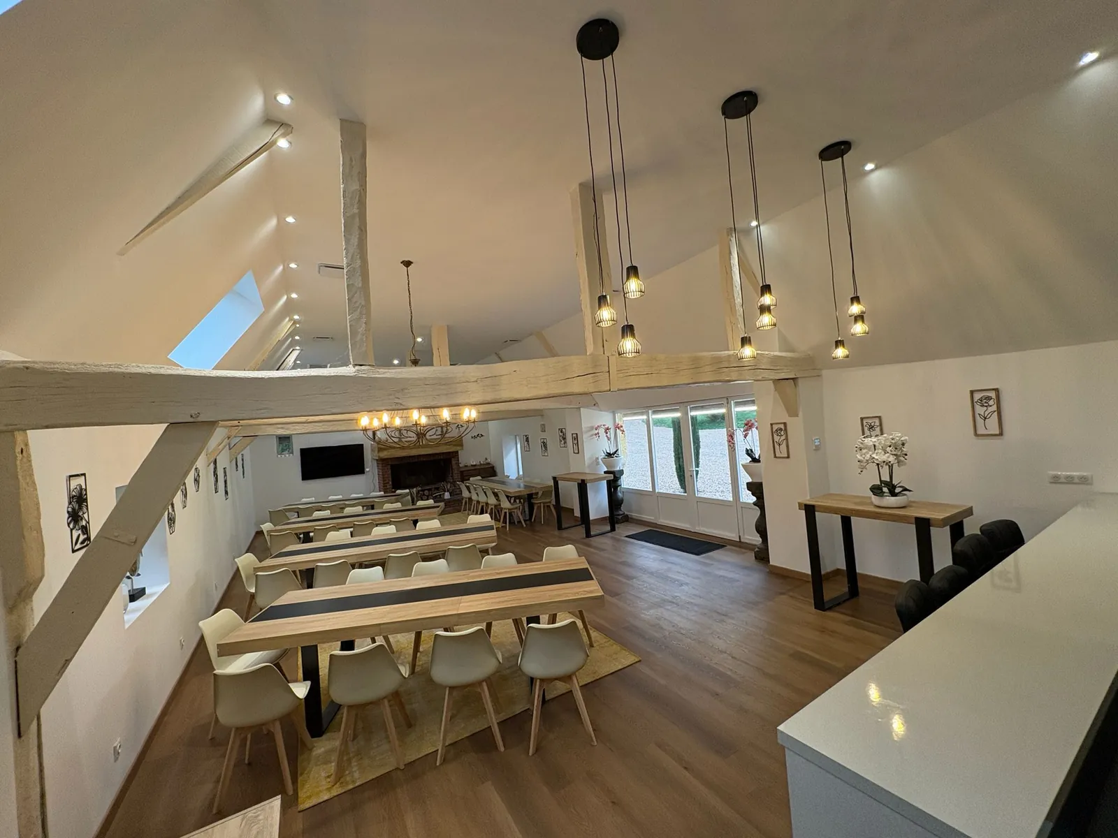 Salle de réception avec longues tables et poutres apparentes à La Haute Barde